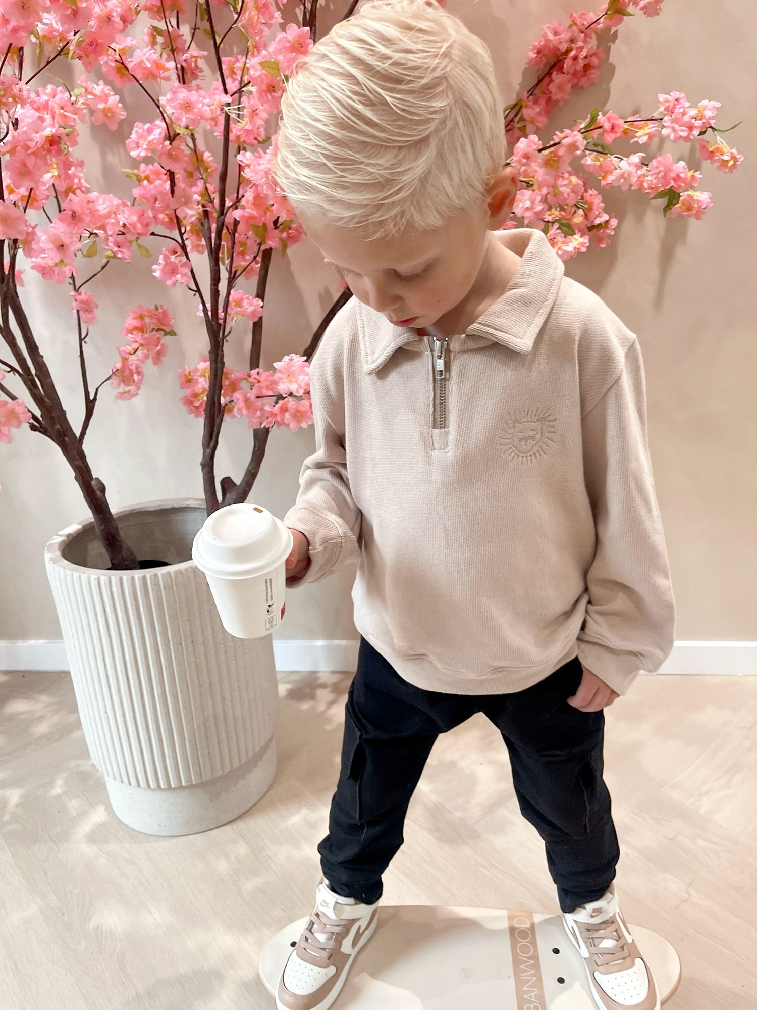 Beige sweater met rits en een geborduurde leeuwen logo en een zwarte cargobroek met zakken voor kinderen