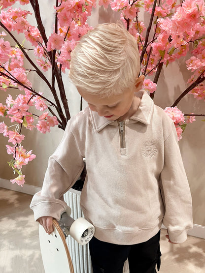 Beige sweater met rits en een geborduurde leeuwen logo en een zwarte cargobroek met zakken voor kinderen