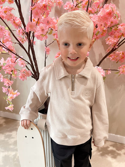 Beige sweater met rits en een geborduurde leeuwen logo en een zwarte cargobroek met zakken voor kinderen