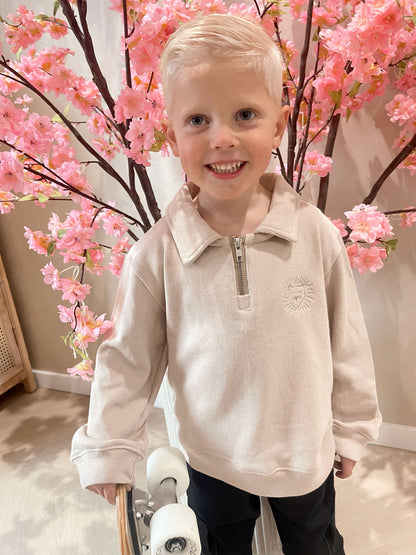 Beige sweater met rits en een geborduurde leeuwen logo en een zwarte cargobroek met zakken voor kinderen