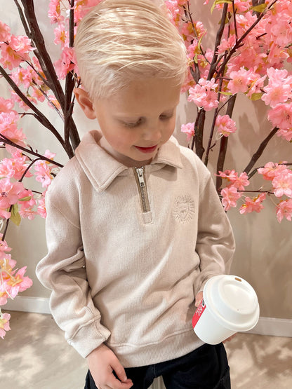 Beige sweater met rits en een geborduurde leeuwen logo en een zwarte cargobroek met zakken voor kinderen