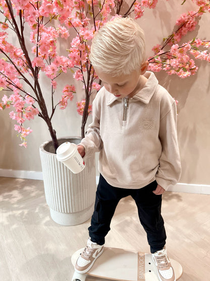Beige sweater met rits en een geborduurde leeuwen logo en een zwarte cargobroek met zakken voor kinderen